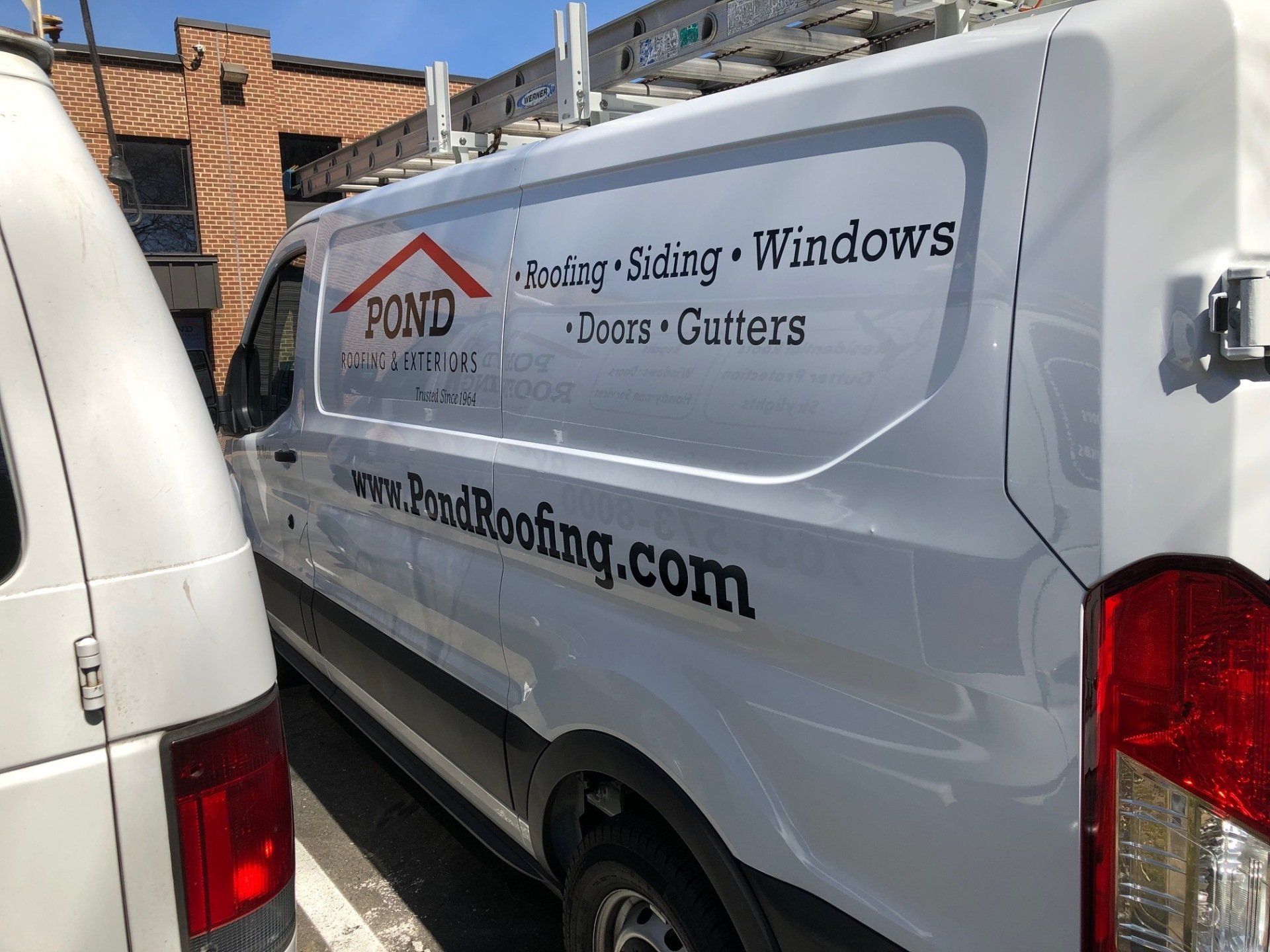 A white van is parked next to another van in a parking lot.