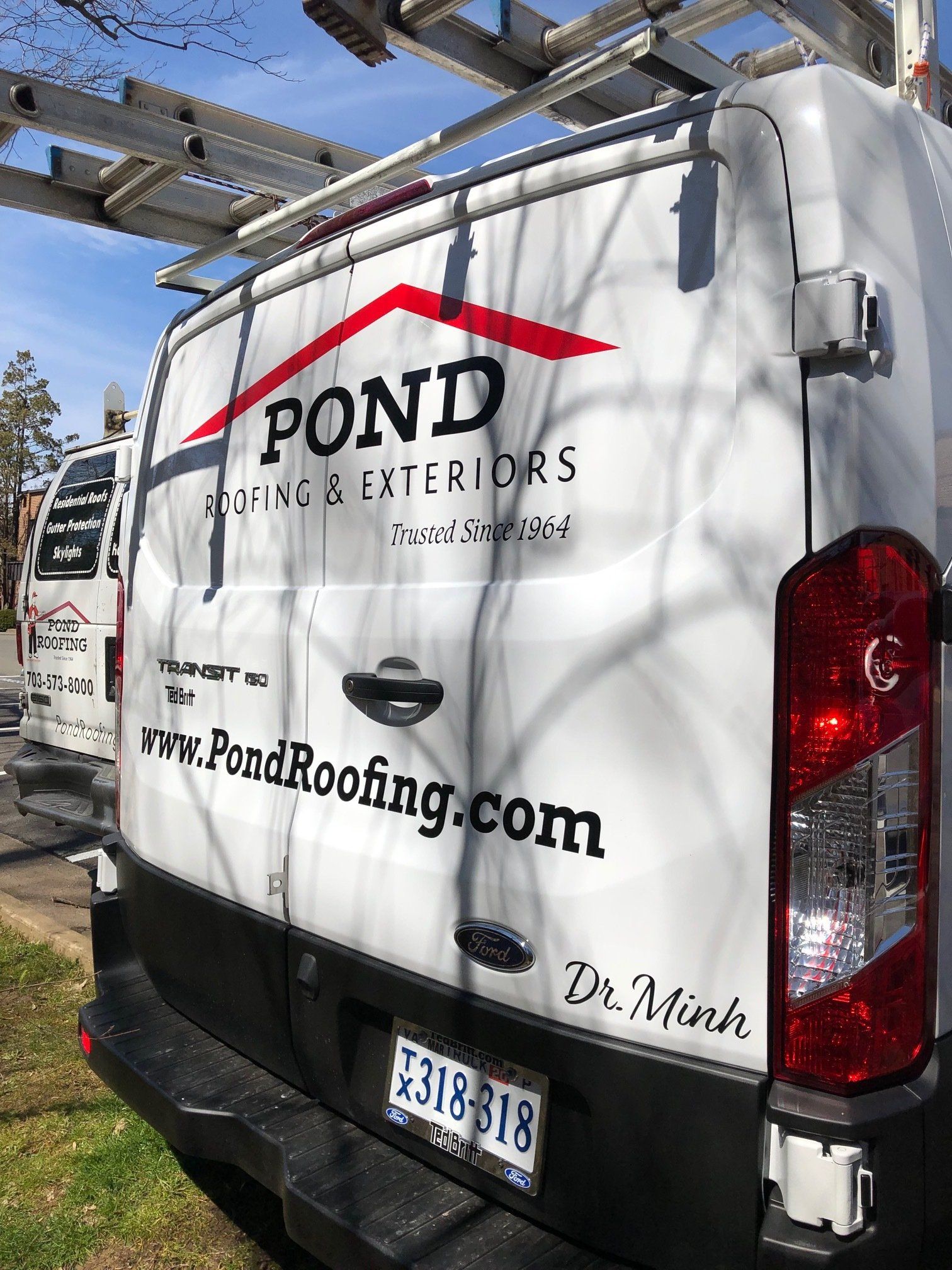 A white van with a red roof is parked on the side of the road.