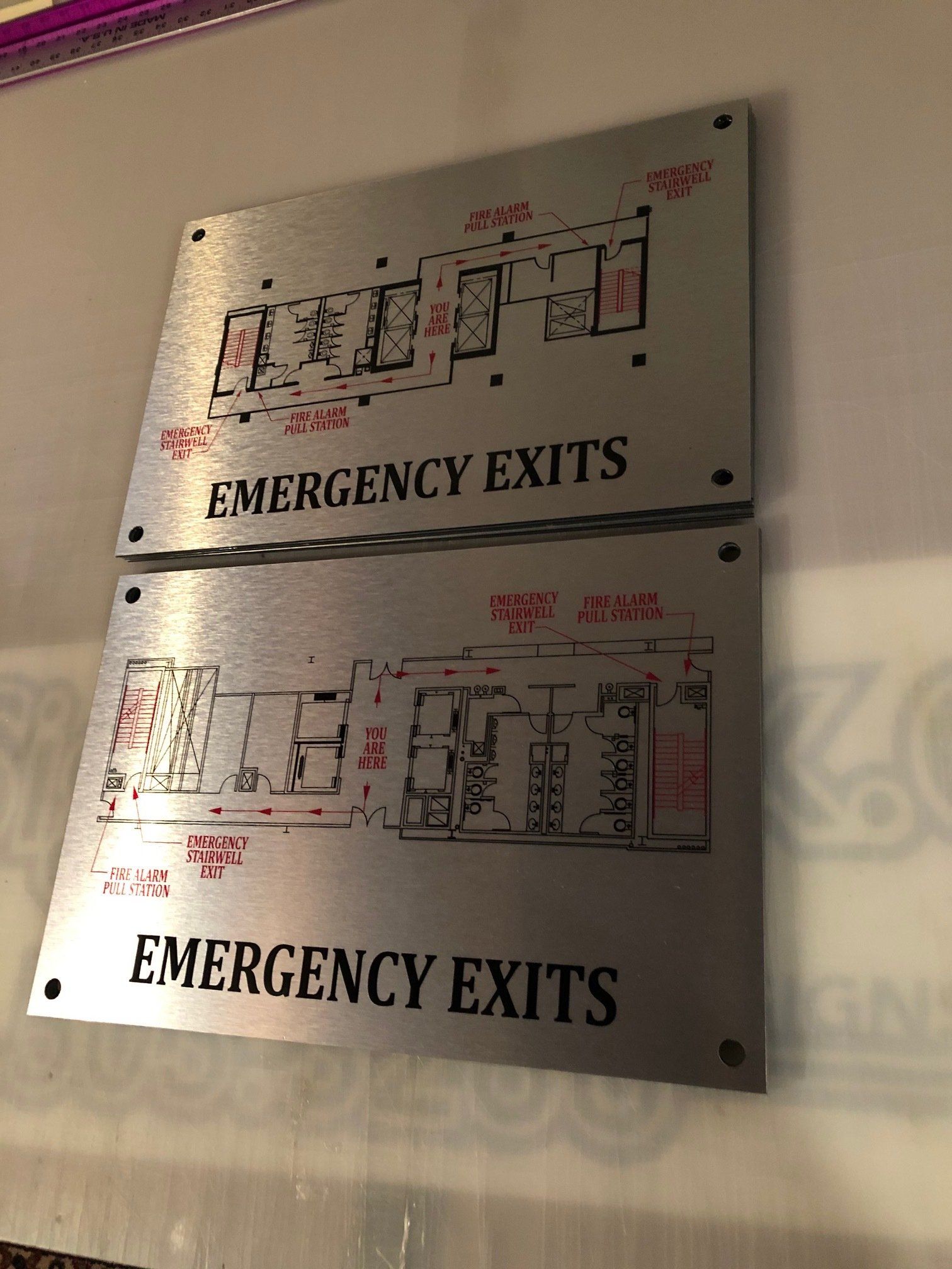 Two emergency exit signs are hanging on a wall