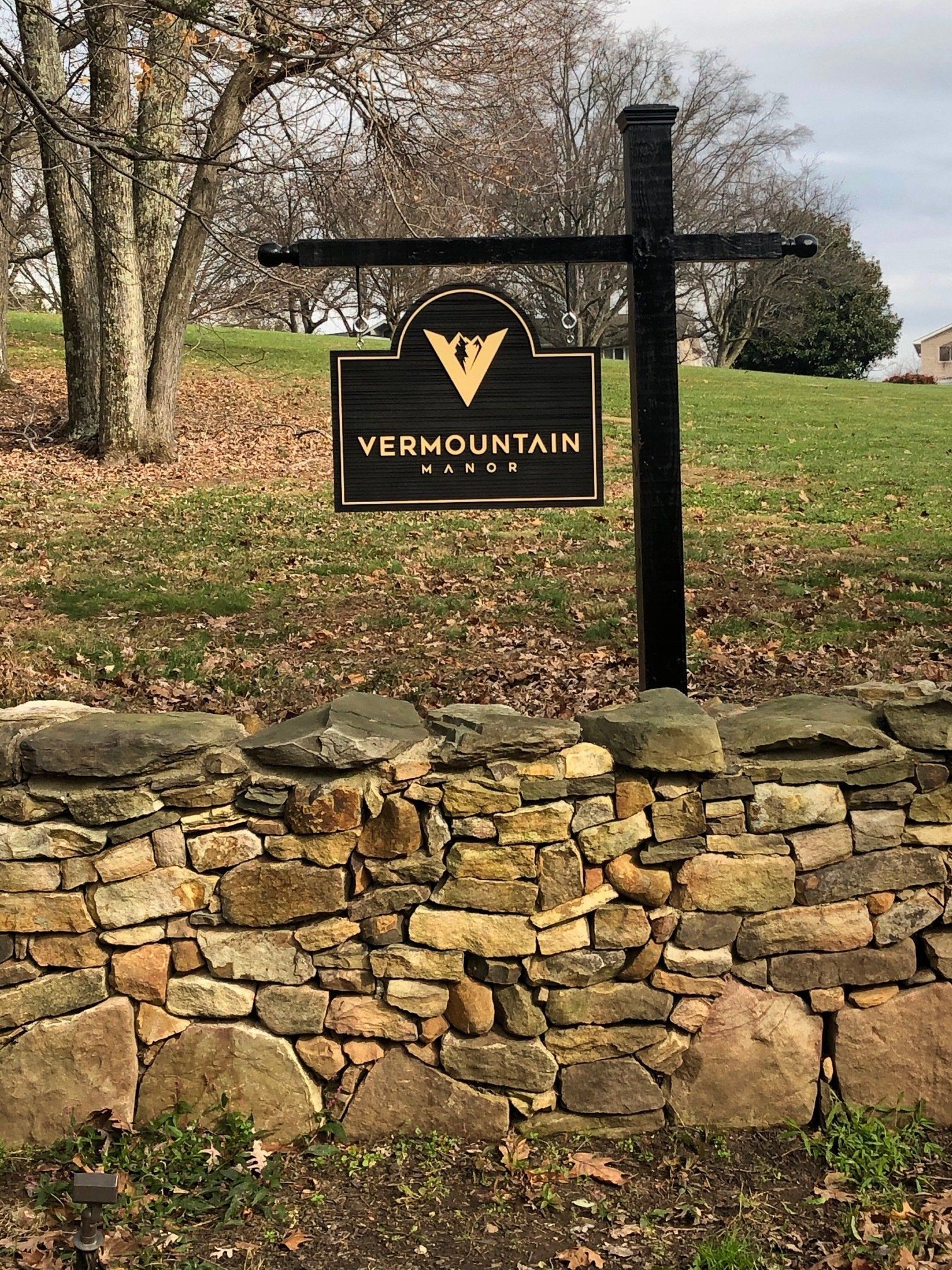 A sign is hanging over a stone wall.