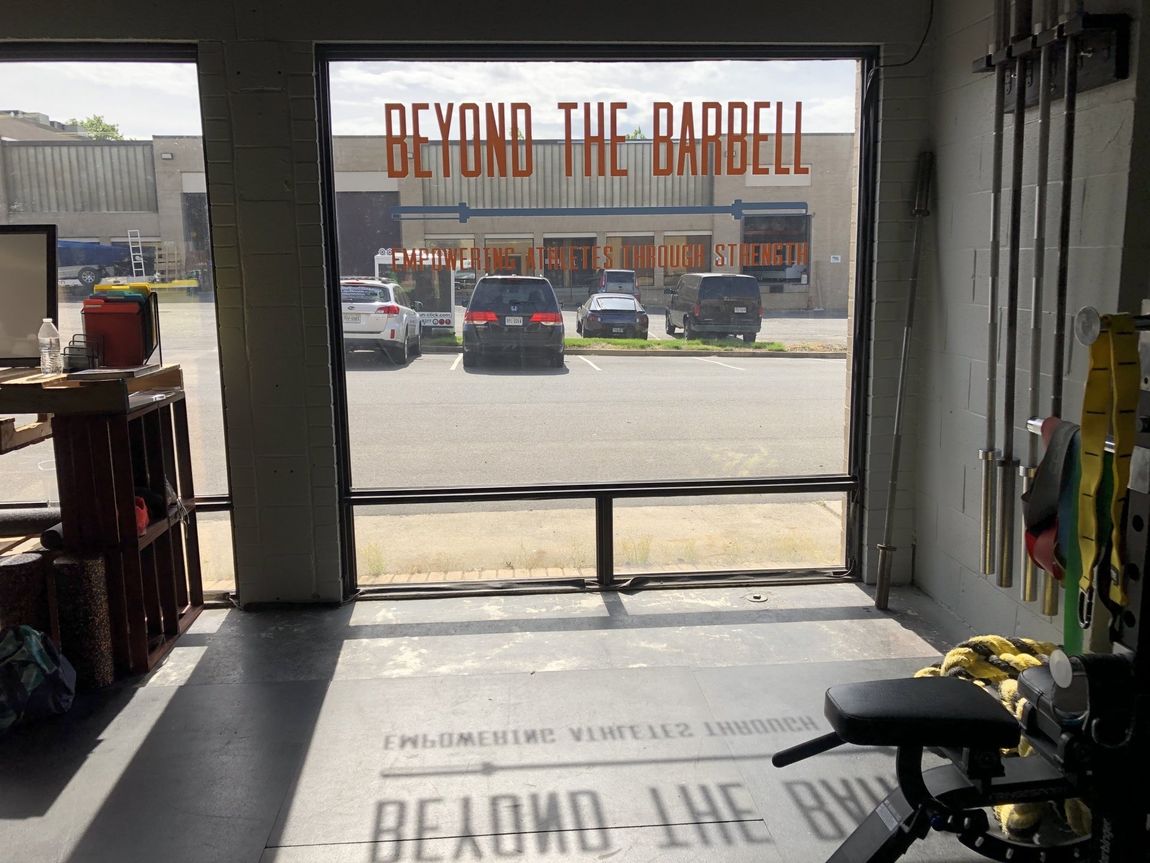 A gym with a window that says beyond the barbell