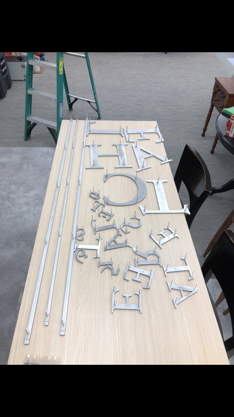 A wooden table with metal letters on it and a ladder in the background.