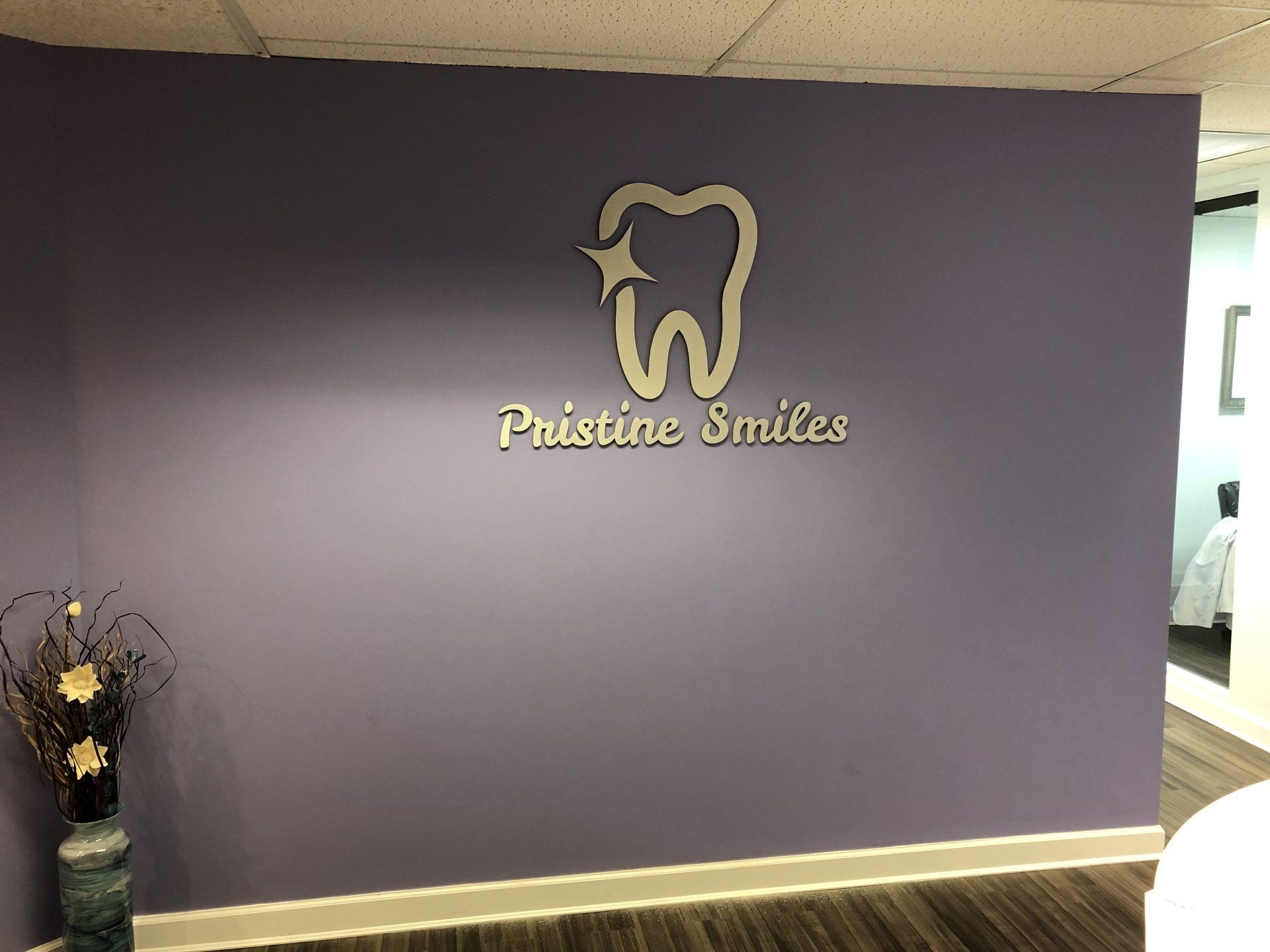 A purple wall with a sign that says pristine smiles on it.