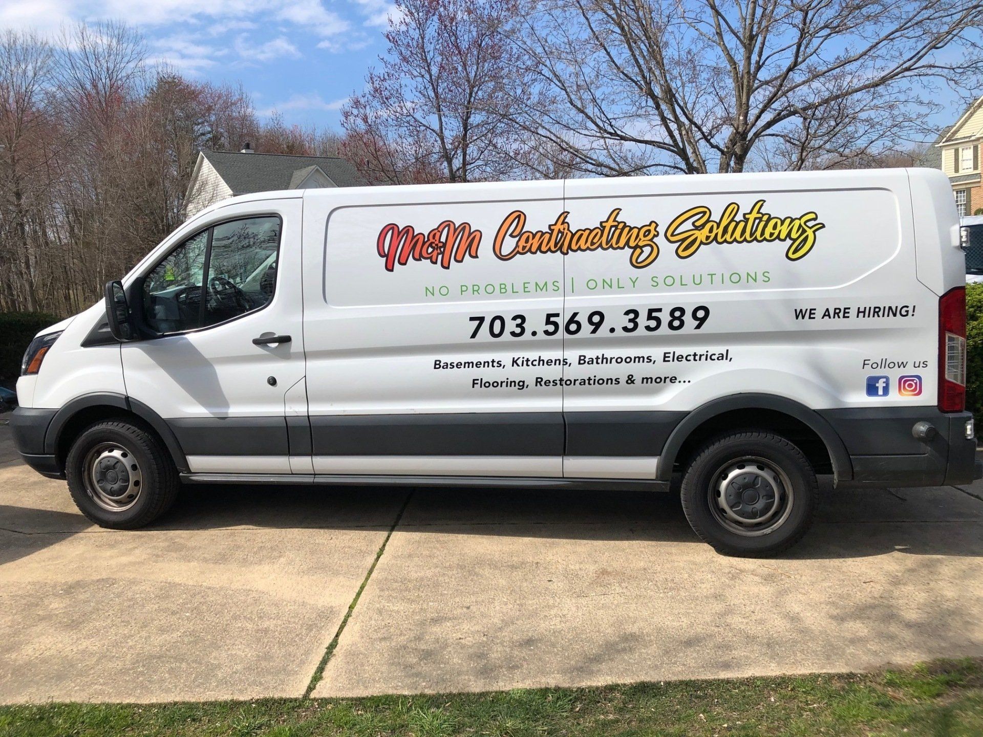 A white van is parked in a driveway in front of a house.