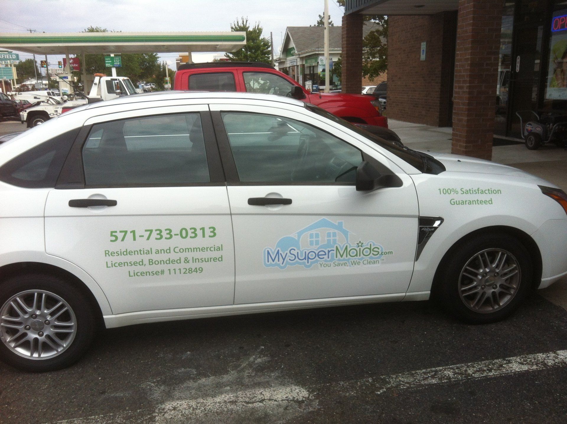 A white car is parked in front of a gas station
