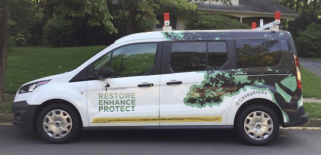 A white van that says restore enhance protect is parked in front of a house.