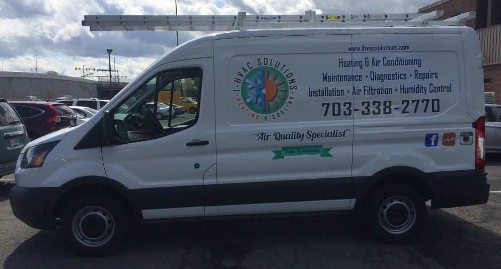 A white van with a ladder on top of it is parked in a parking lot.