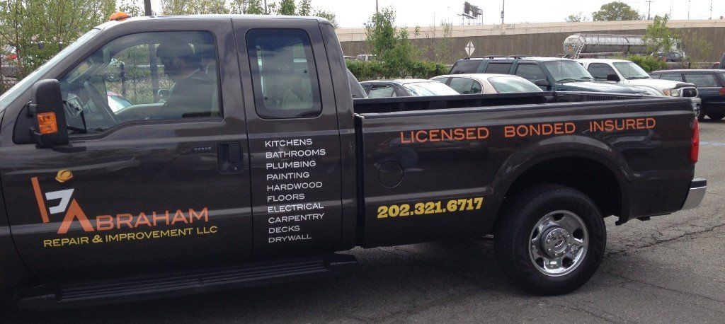 A black truck with abraham written on the side is parked in a parking lot
