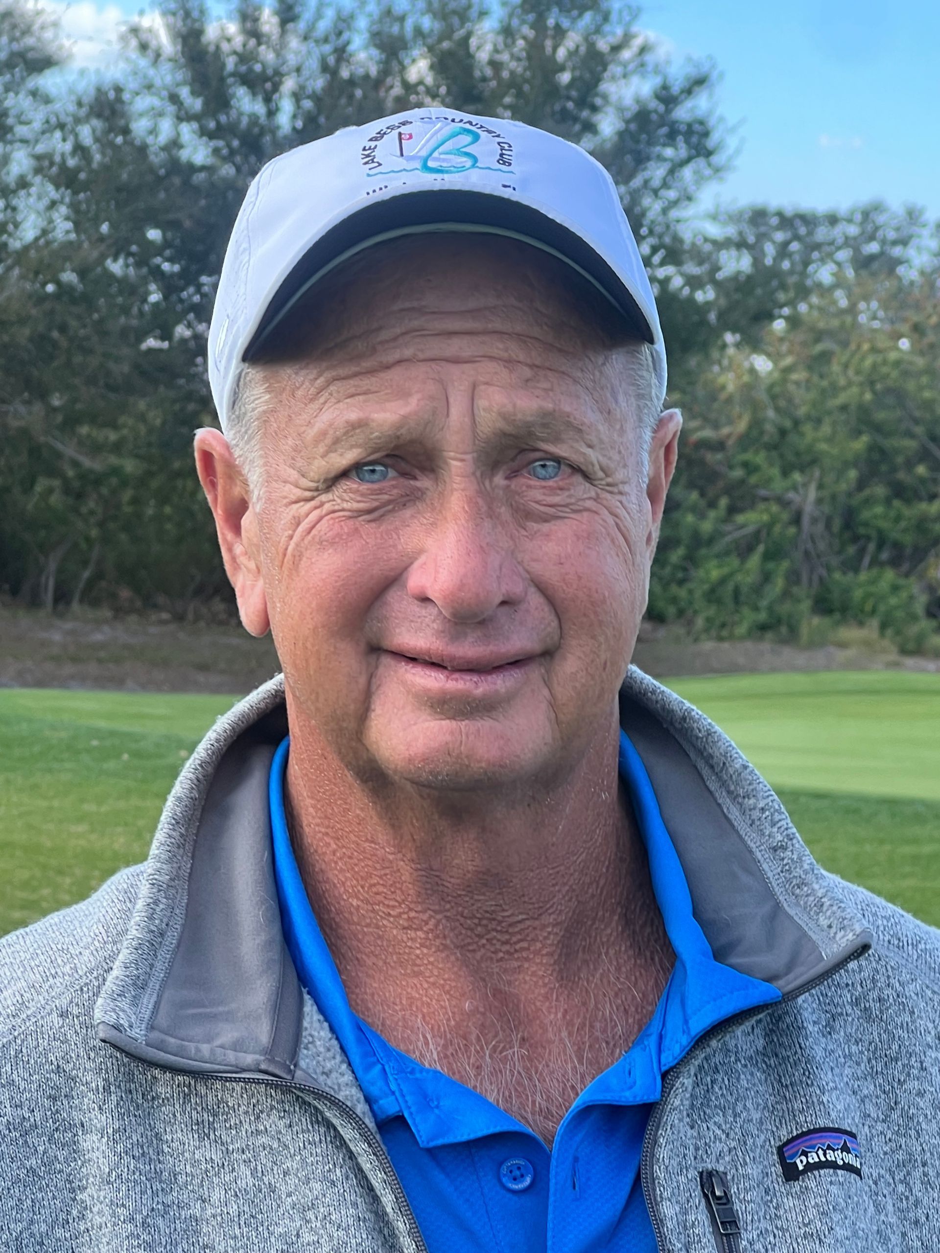 A man in a blue polo shirt is smiling for the camera.