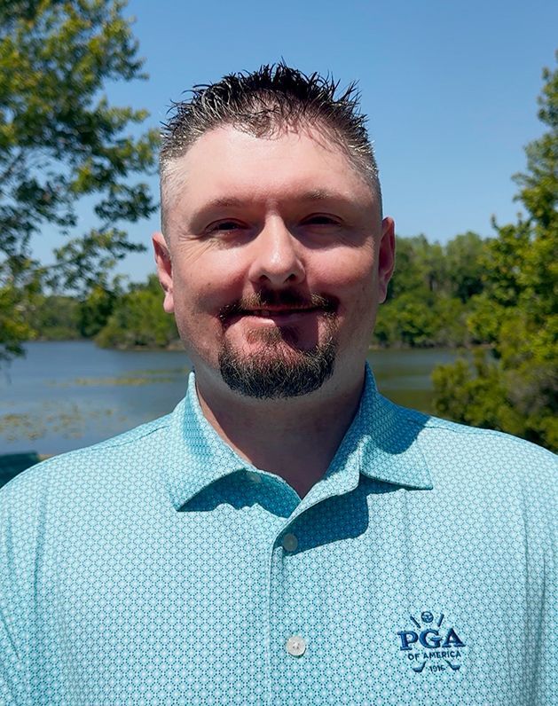 A man in a blue polo shirt is smiling for the camera.