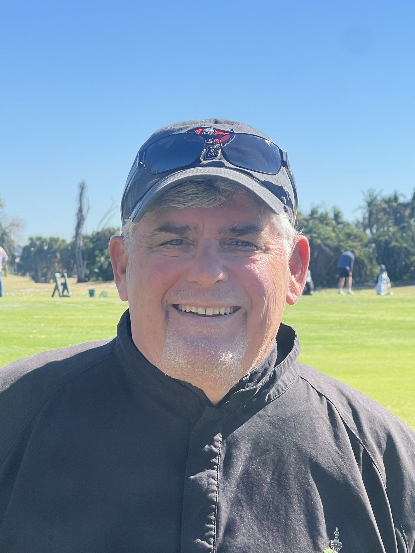 A man in a blue polo shirt is smiling for the camera.