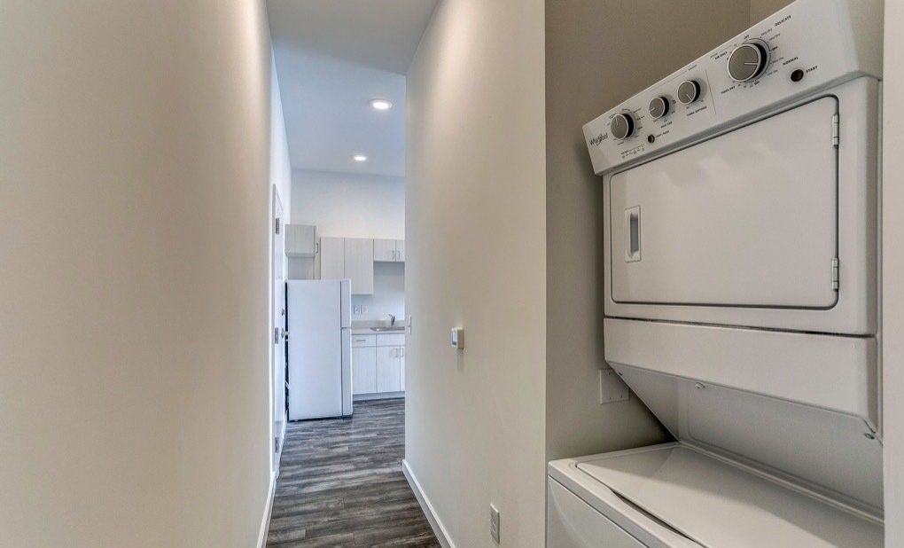 Photo showing a hallway with the kitchen in the background and washer and dryer in the foreground