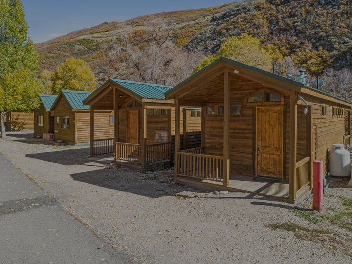 A row of small wooden cabins sitting next to each other on a dirt road.