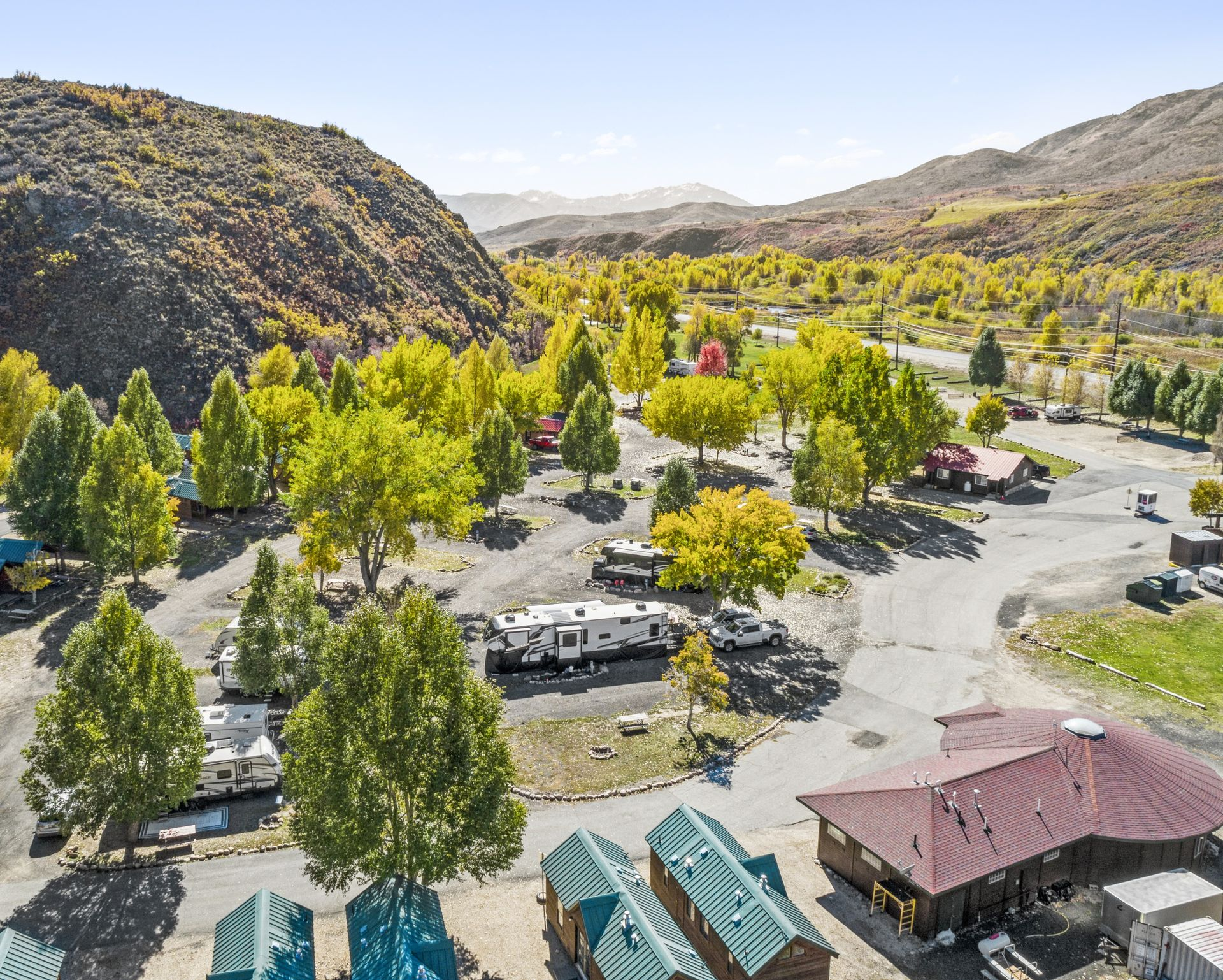 A row of rvs are parked in a gravel lot.