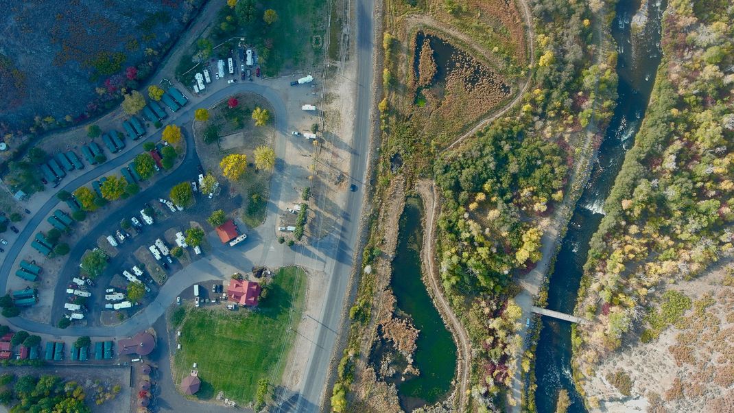 Aerial view of River's Edge RV Resort in Heber City, Utah, showing RV sites, cabins, and the Provo River alongside fall foliage