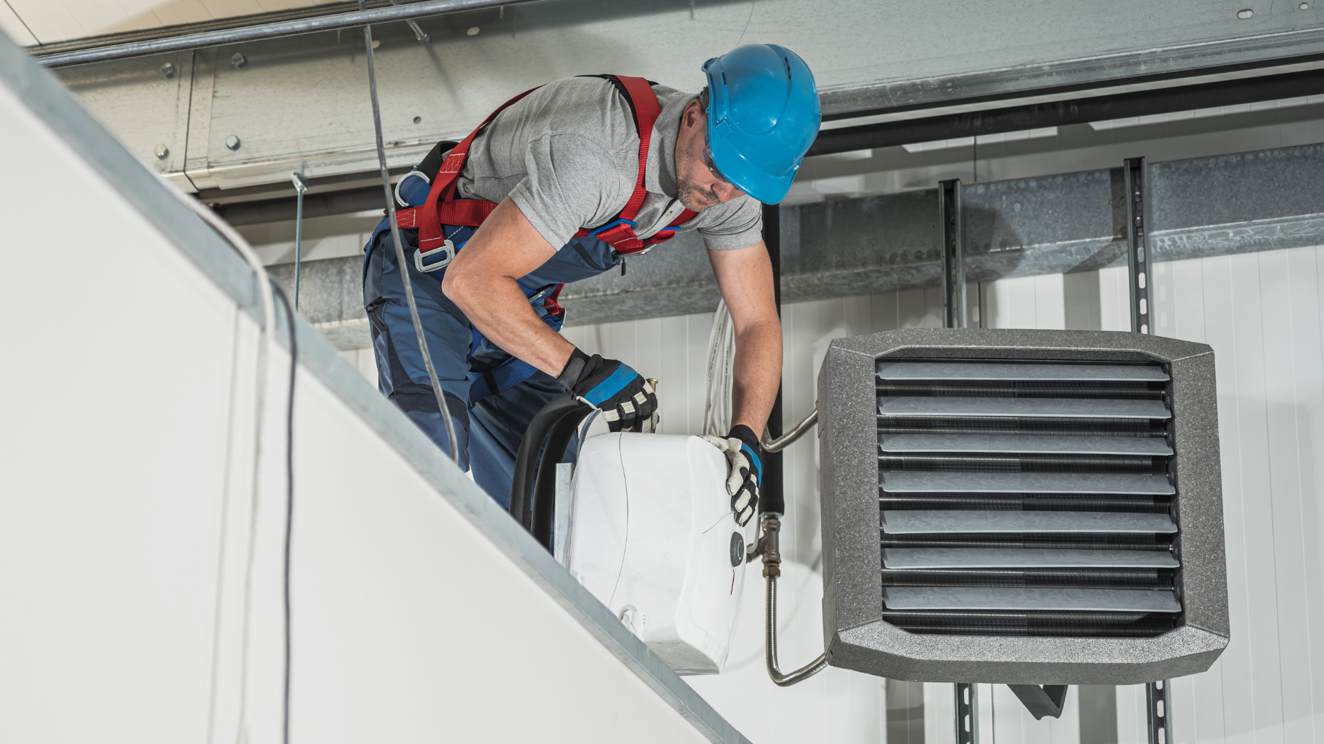 A man is working on a heater on the ceiling of a building.