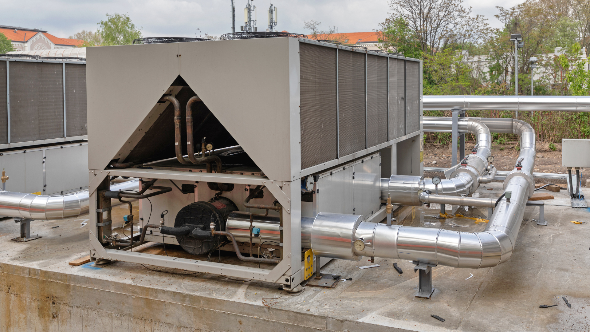 A large machine is sitting on top of a concrete platform surrounded by pipes.