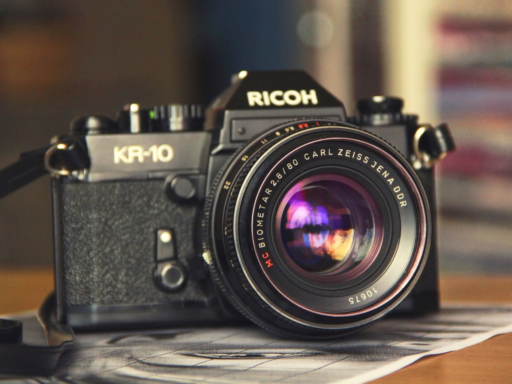 a black ricoh camera is sitting on a table .