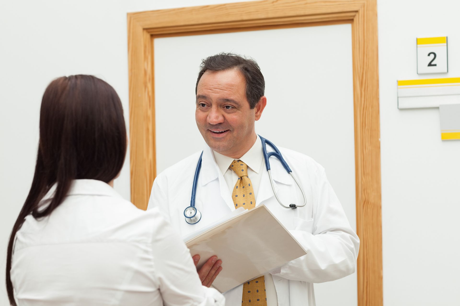 Bilingual doctor holding a file, consulting with a female multicultural patient. Bilingual doctor holding a file, consulting with a female multicultural patient.