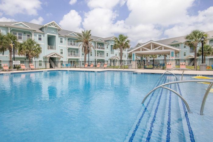 Pool with apartments in background on a sunny day.