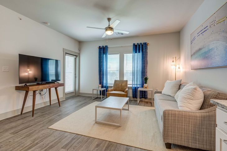 Living room with sofa, TV, and blue curtains.