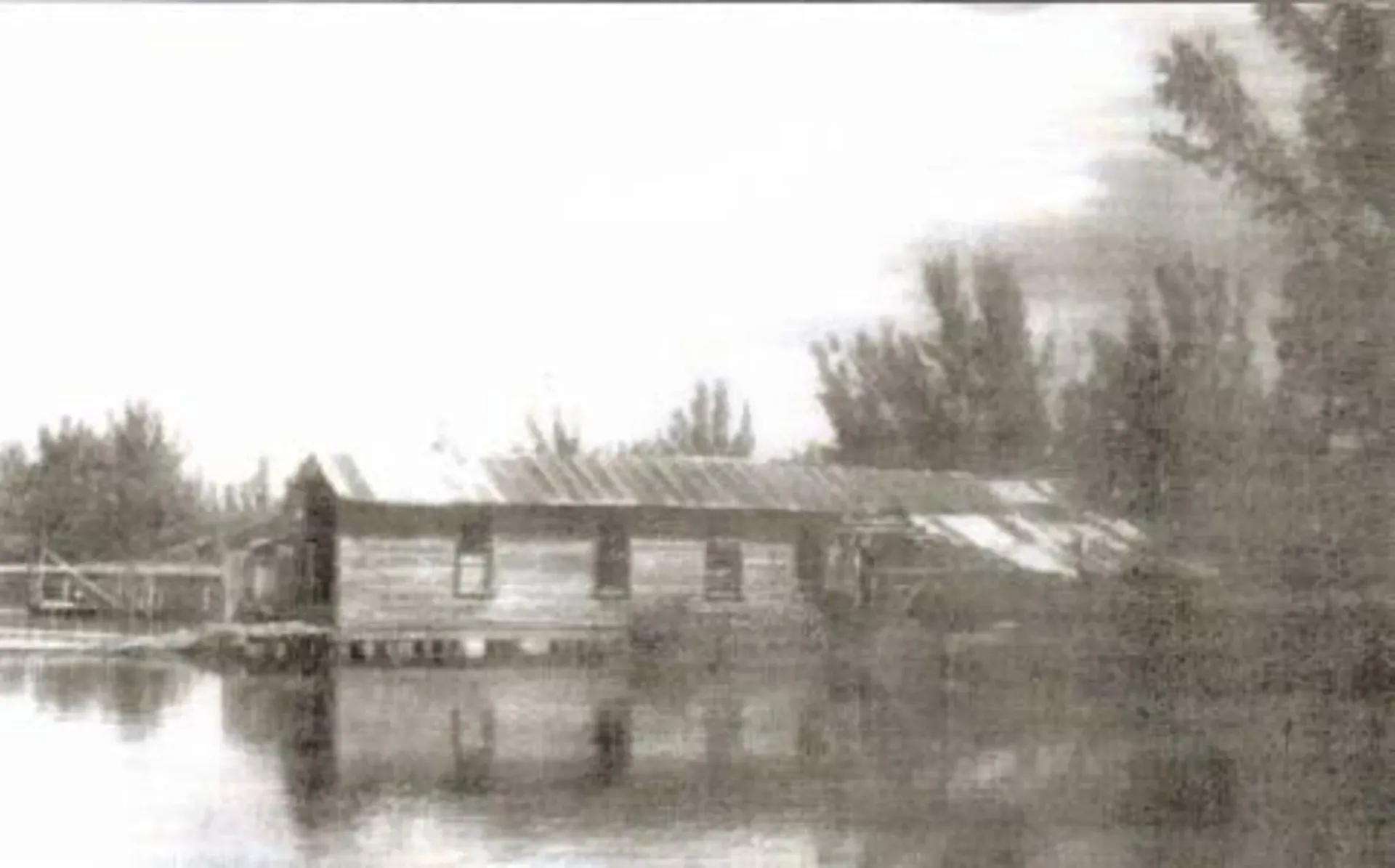 A black and white photo of a house in the middle of a lake.