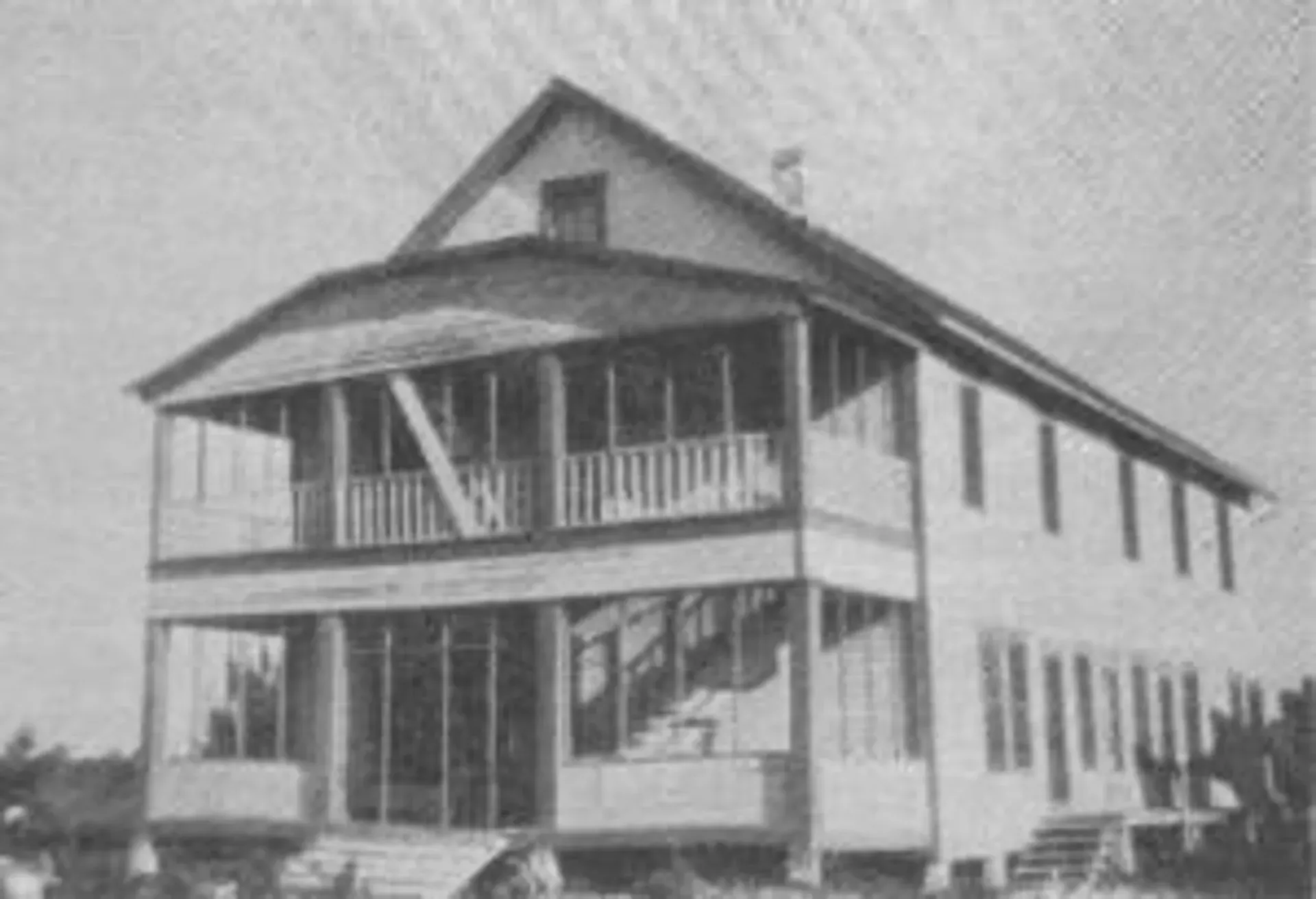A black and white photo of a large house with a porch
