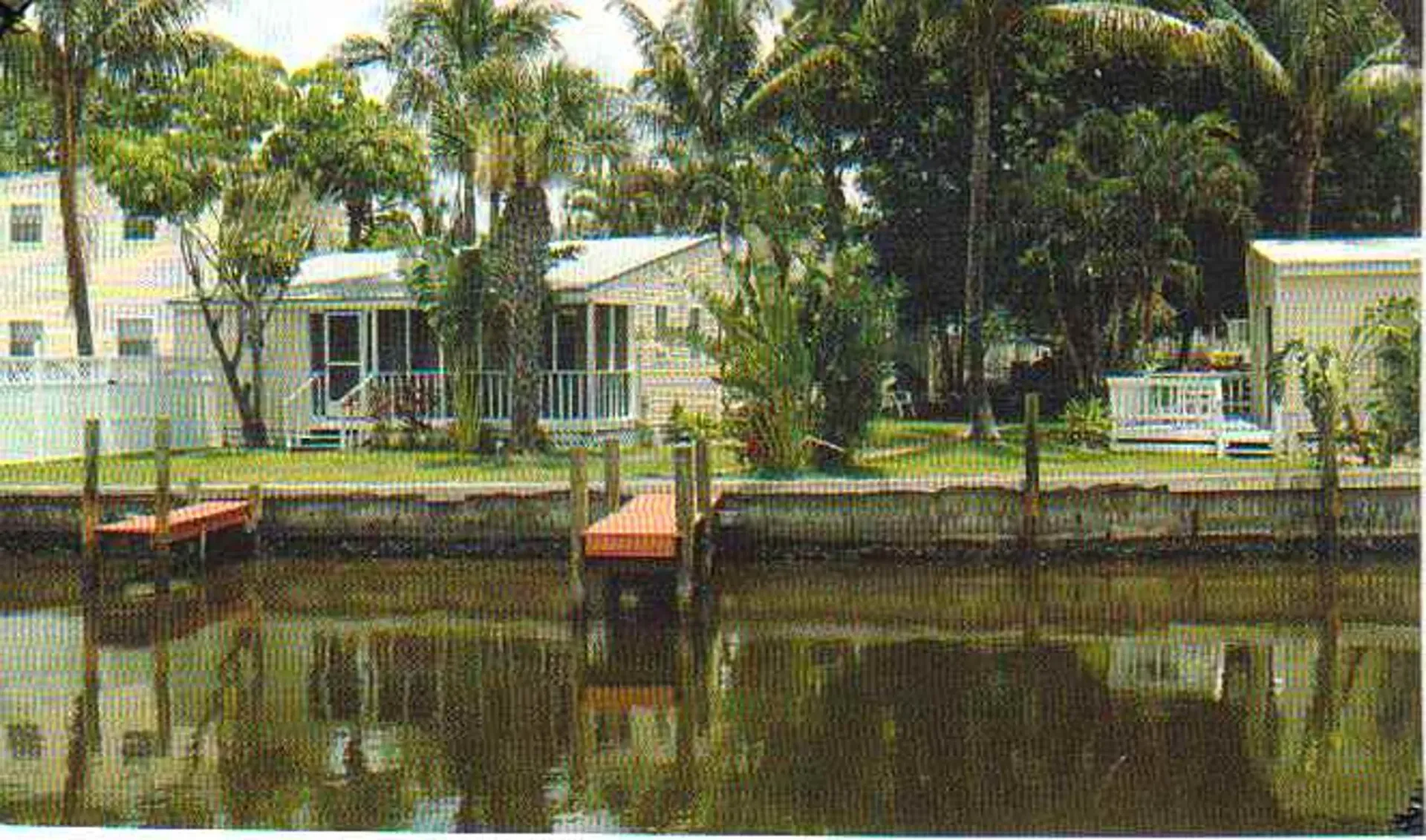 A house is sitting next to a body of water with a dock in front of it.