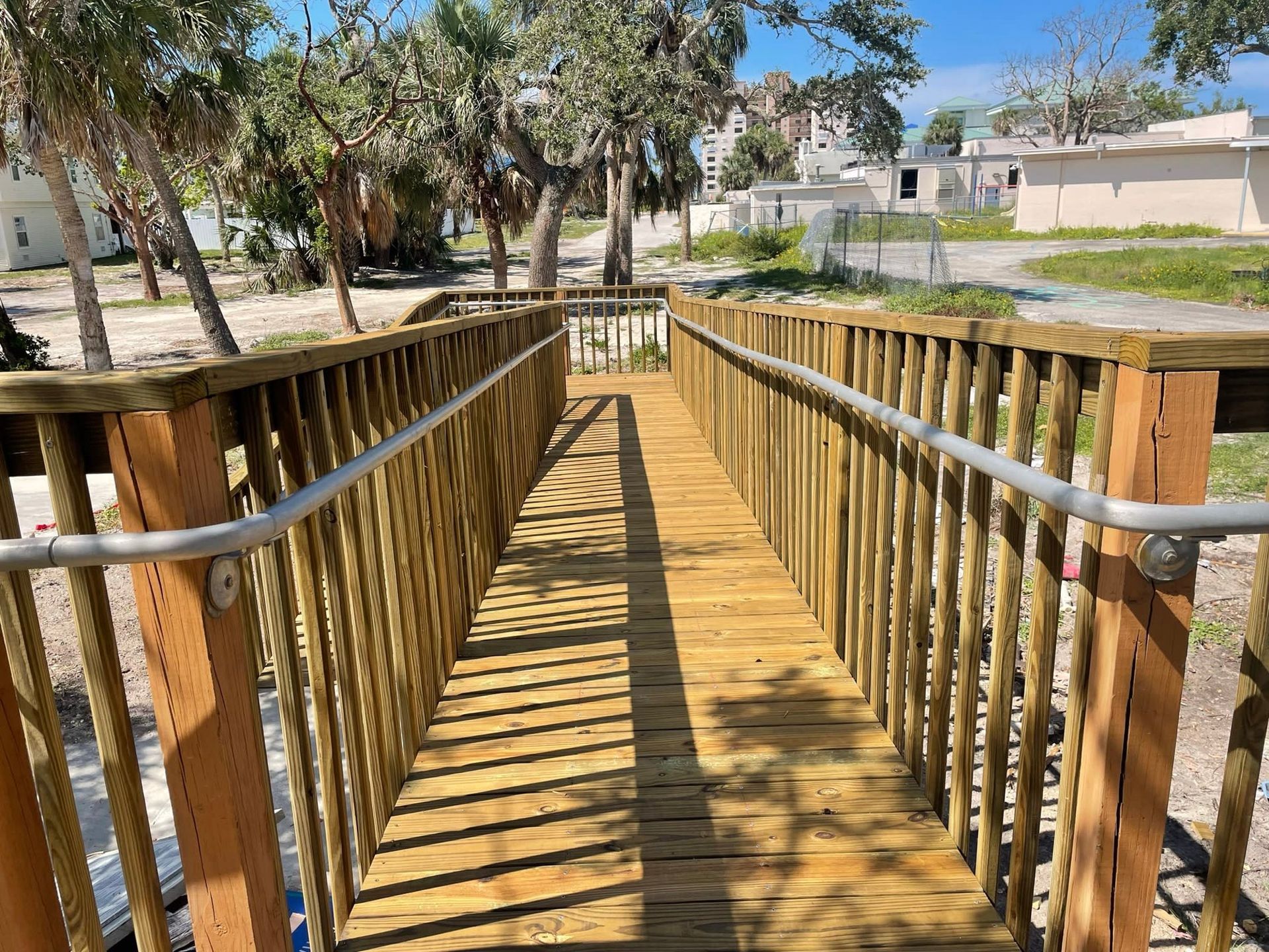 A wooden bridge with a metal railing is going over a body of water.
