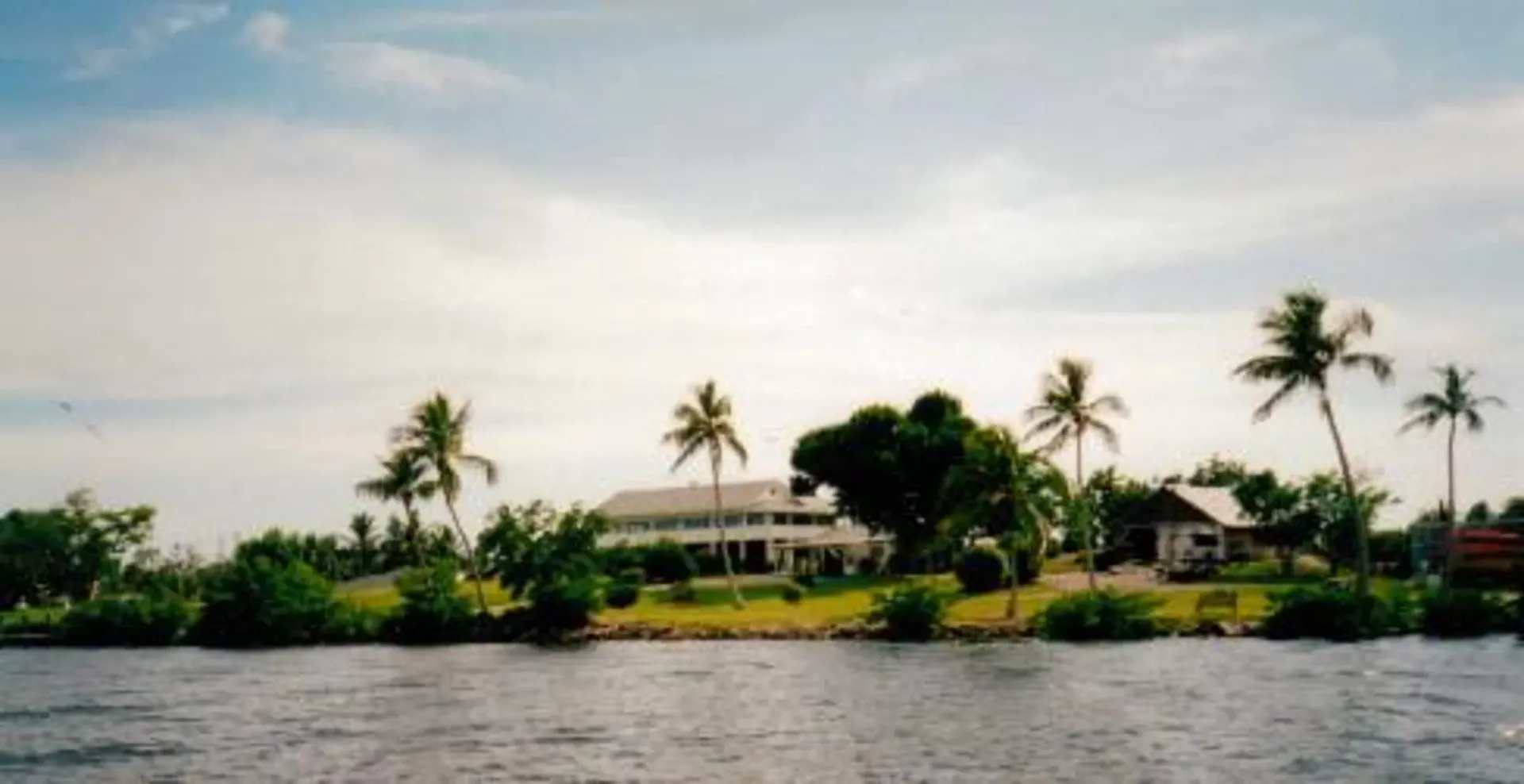 A house sits on a small island in the middle of a body of water