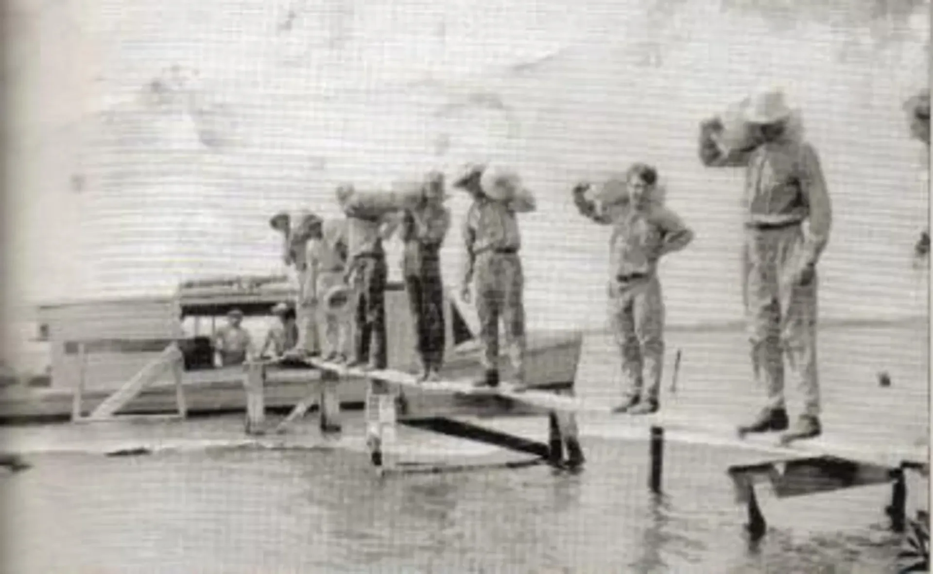 A black and white photo of a group of men standing on a dock