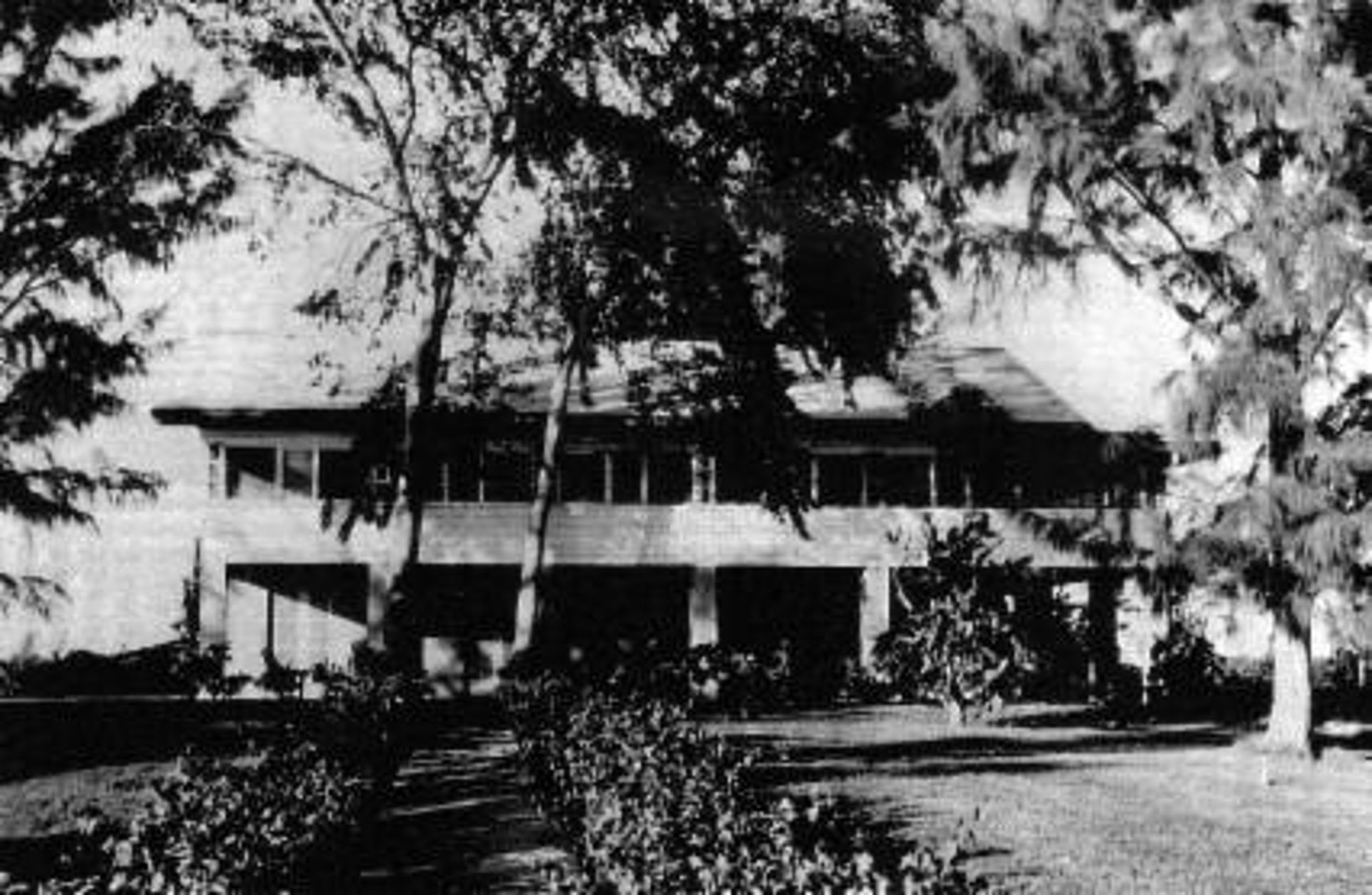 A black and white photo of a large house surrounded by trees