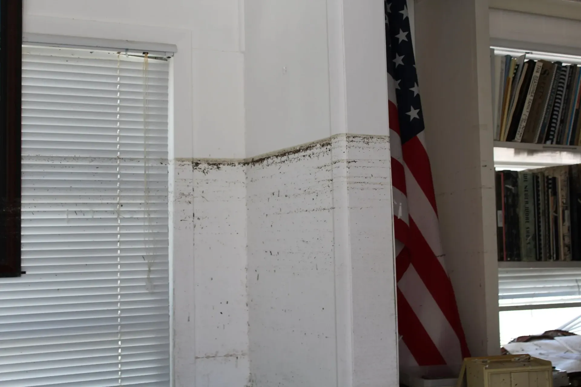 An american flag is hanging on a wall next to a window
