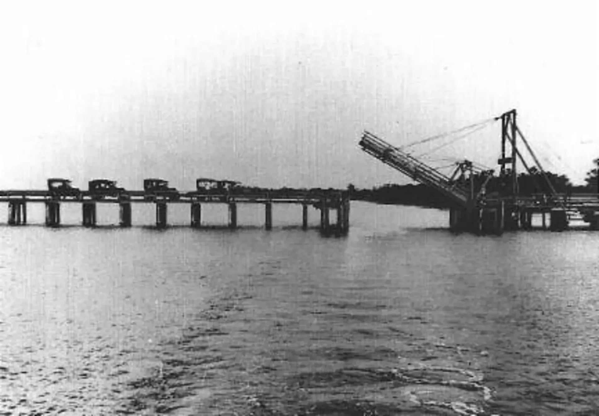 A black and white photo of a bridge over a body of water.