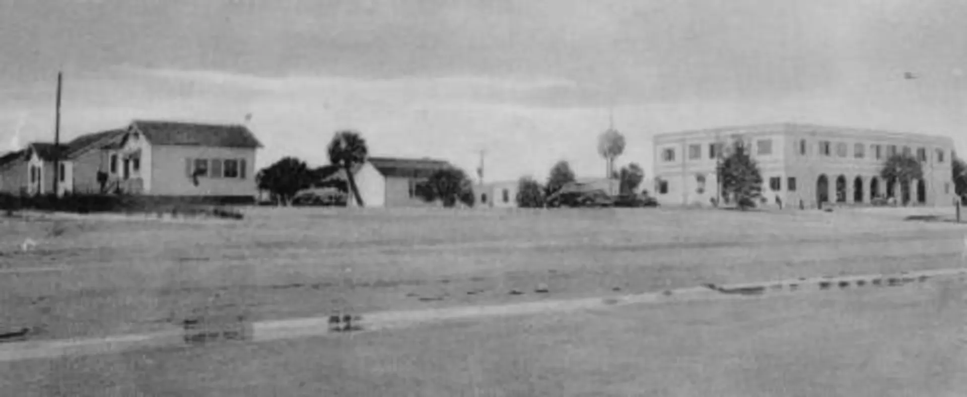 A black and white photo of a row of houses with a large building in the background.