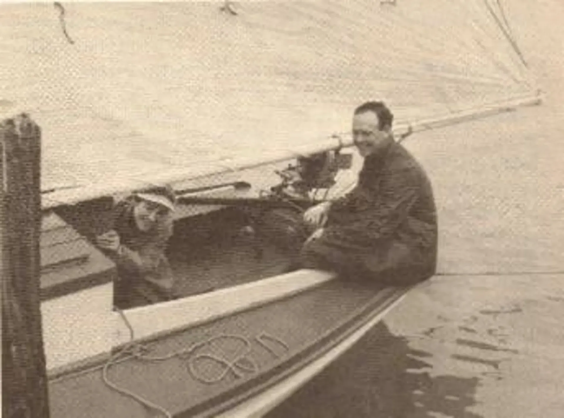 A man is sitting on the back of a boat in the water.