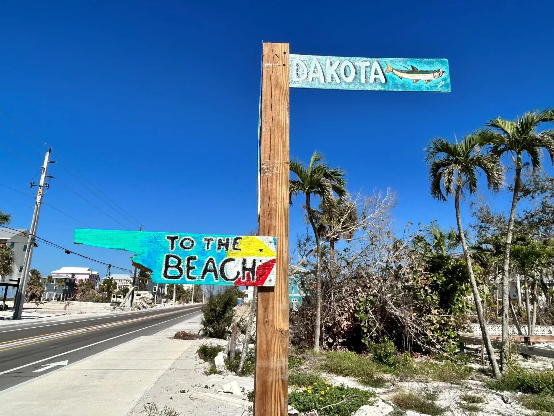 A wooden post with a sign on it that says `` to the beach ''.