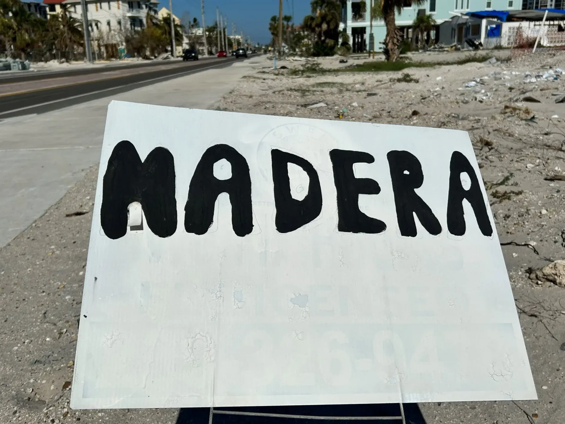 A sign on the beach that says madera in black letters