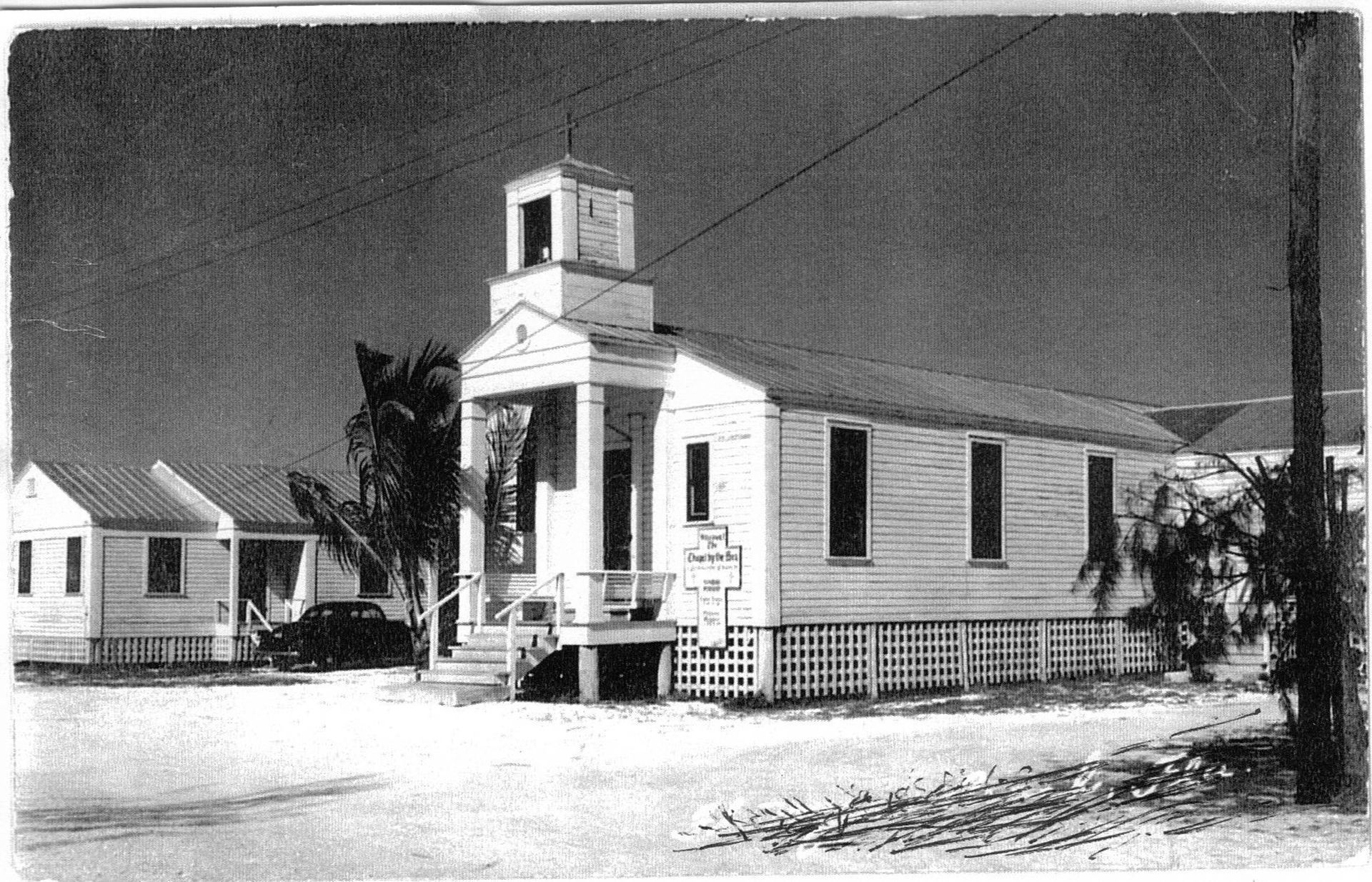 A black and white photo of a church with a clock tower.
