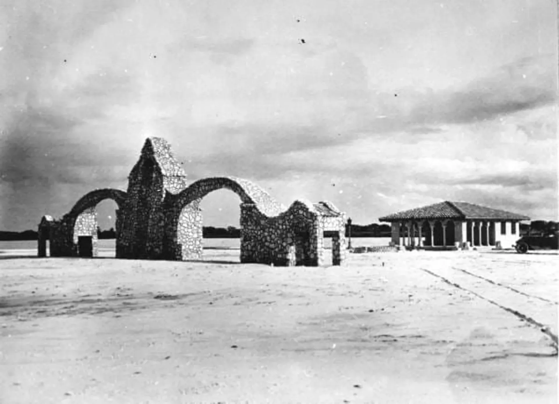 A black and white photo of a building in the middle of a field.