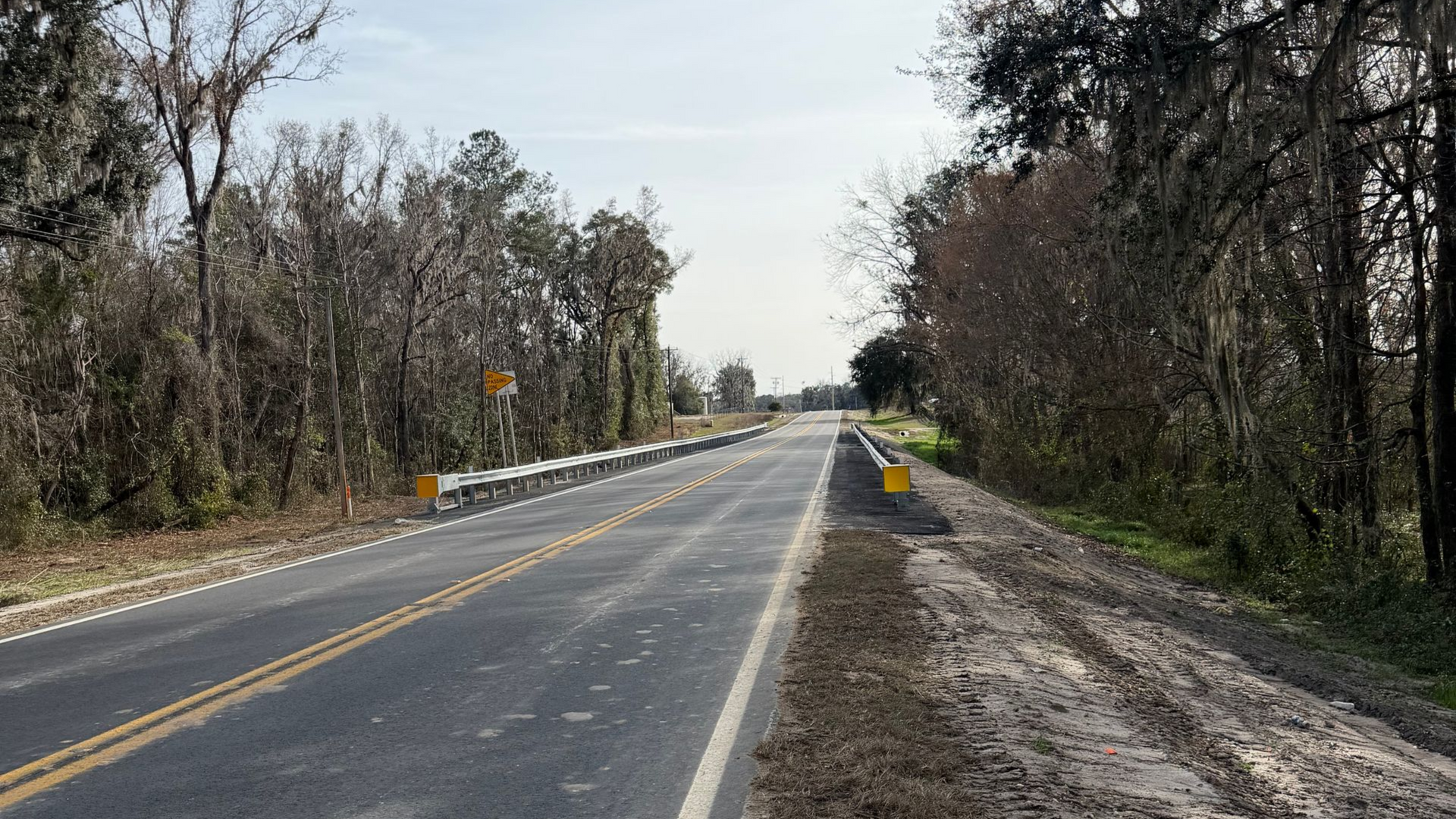 Freshly paved rural roadway with newly installed guardrails and highway safety improvements in a Florida roadway construction project