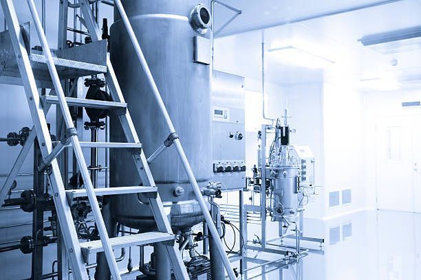 A blue and white photo of a factory with stairs and machinery.
