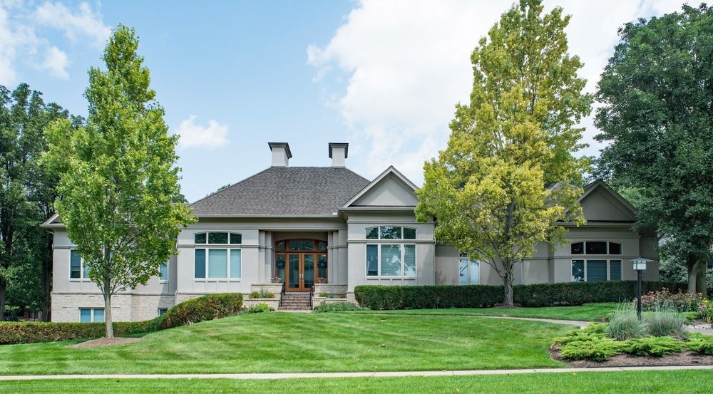 A large house with a lush green lawn and trees in front of it.