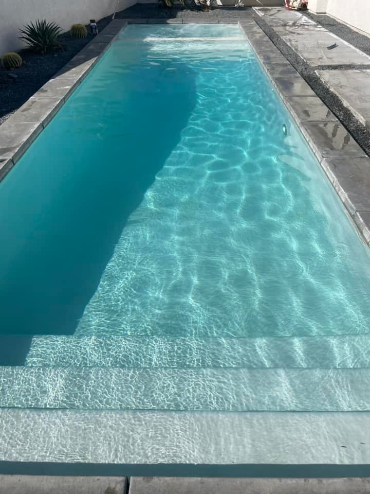 Long, rectangular swimming pool filled with turquoise water, with built-in steps.