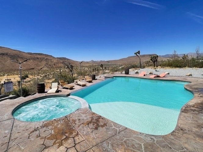 Pool and jacuzzi surrounded by desert landscape under a clear blue sky.