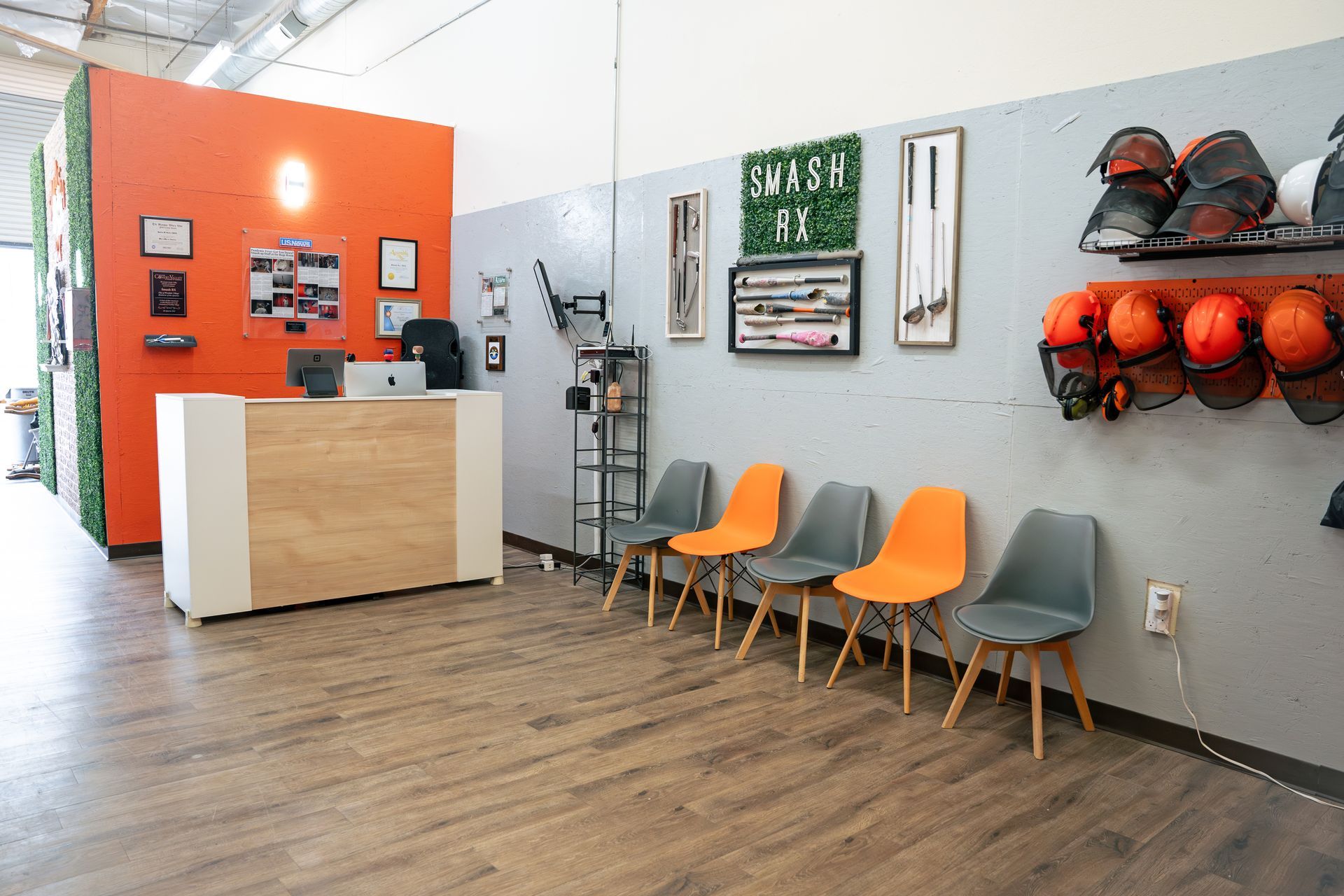 Reception area with orange and gray chairs, orange accent wall, and wood-look flooring.