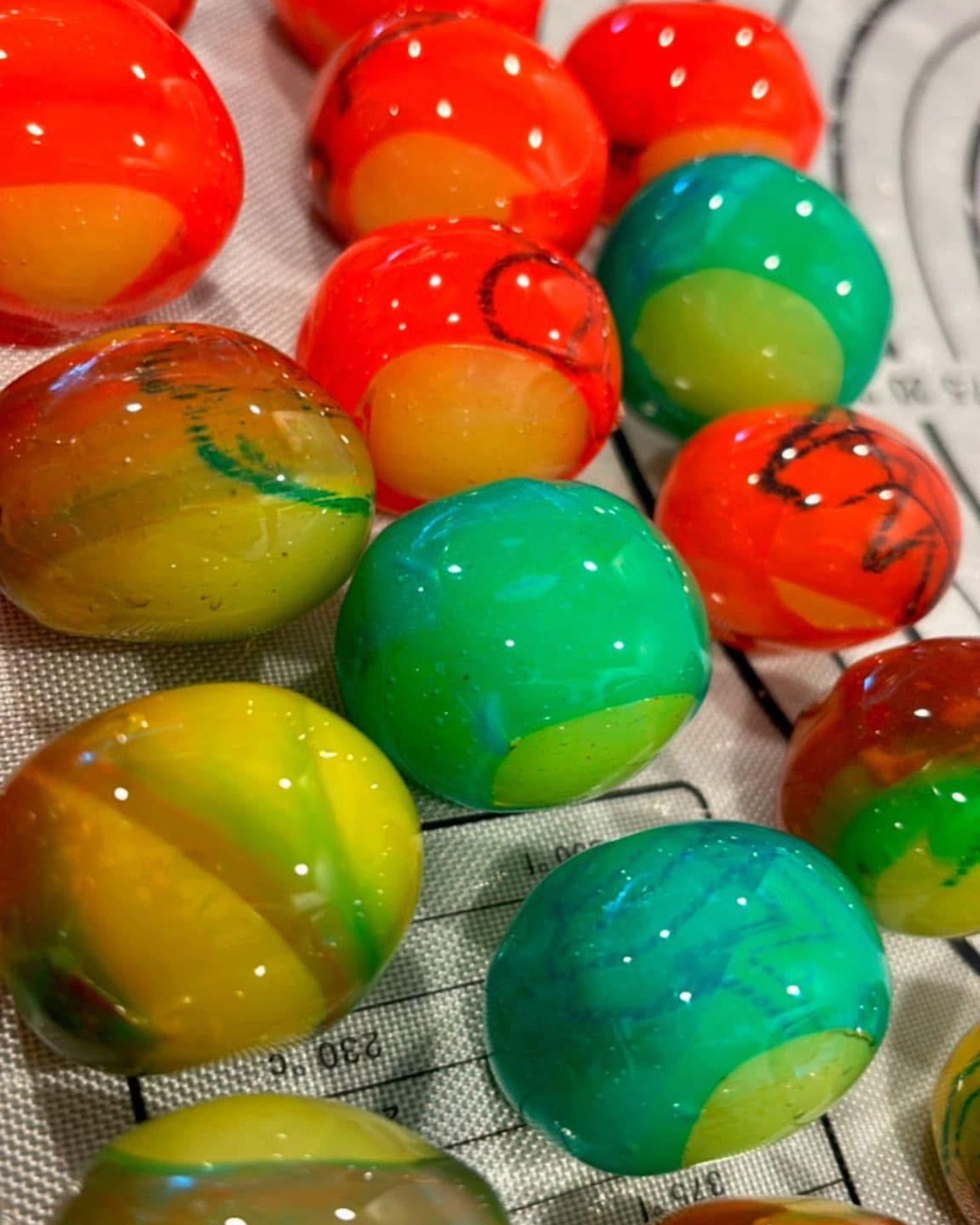 Colorful, round confections with swirls of green, orange, and yellow on a white surface.