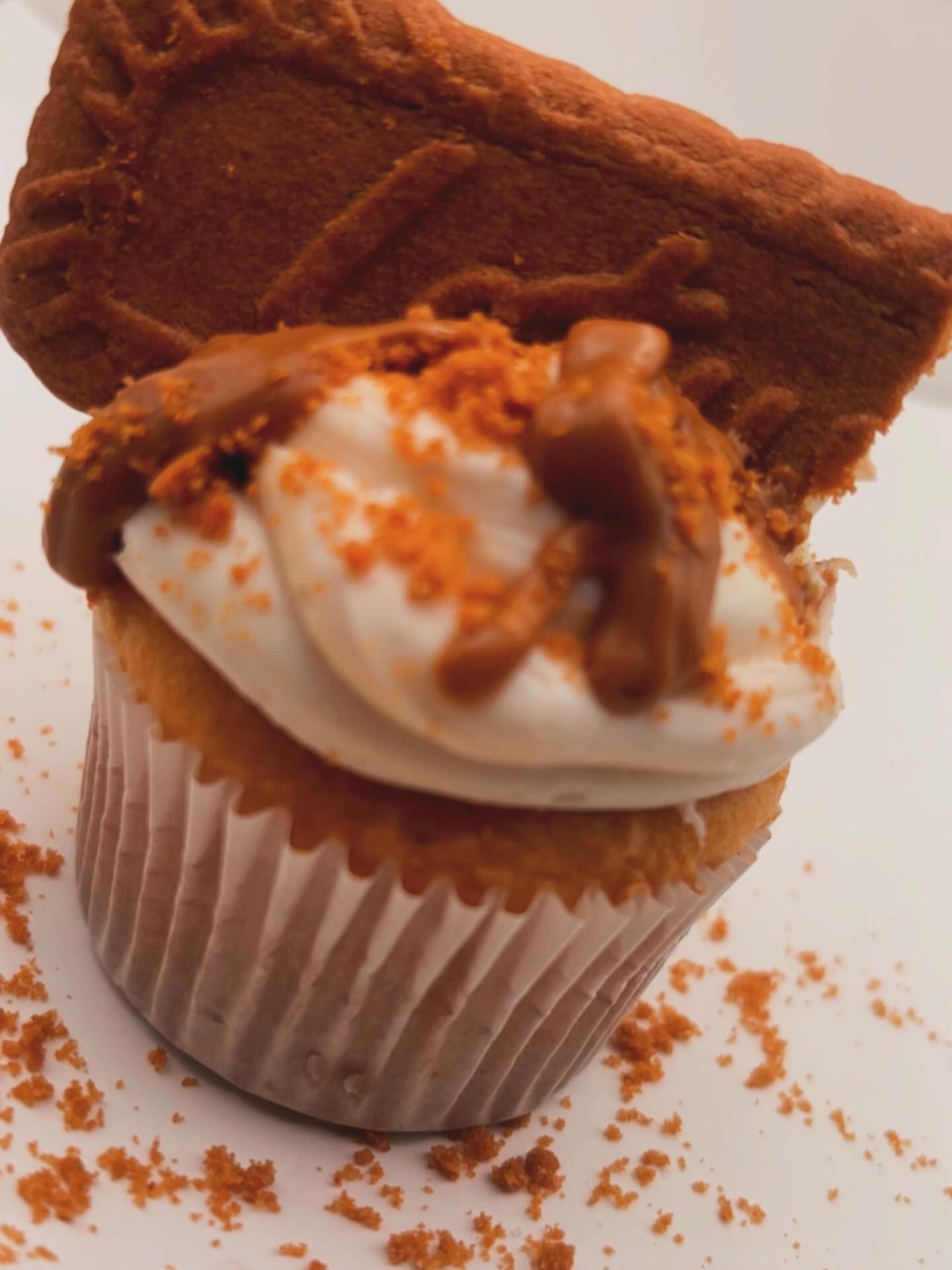 Cupcake with white frosting, cookie, and crushed cookie crumbs.