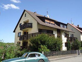 Ein grünes Auto parkt vor einem großen Haus.