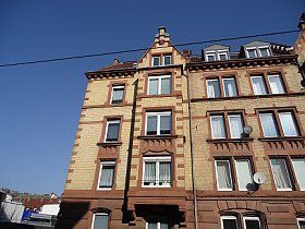 Ein großes Backsteingebäude mit vielen Fenstern vor einem blauen Himmel.